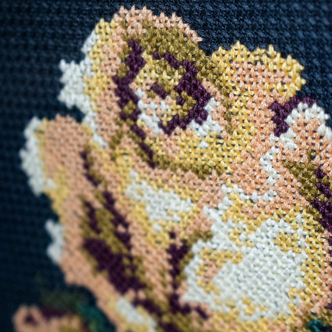 Close-up fragment of “A Rose in a Tall Glass”: the texture of hand-stitched crosses