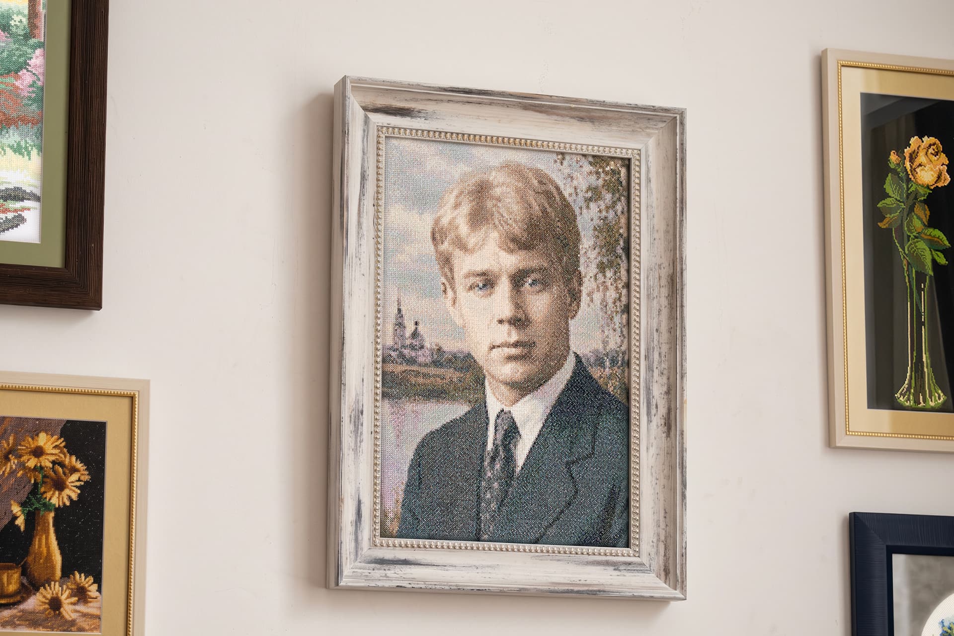 The finished portrait behind glass in a whitewashed frame, hung among other works on a gallery wall